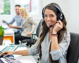 Imagem de uma mulher jovem e sorridente em um call center olhando para a câmera