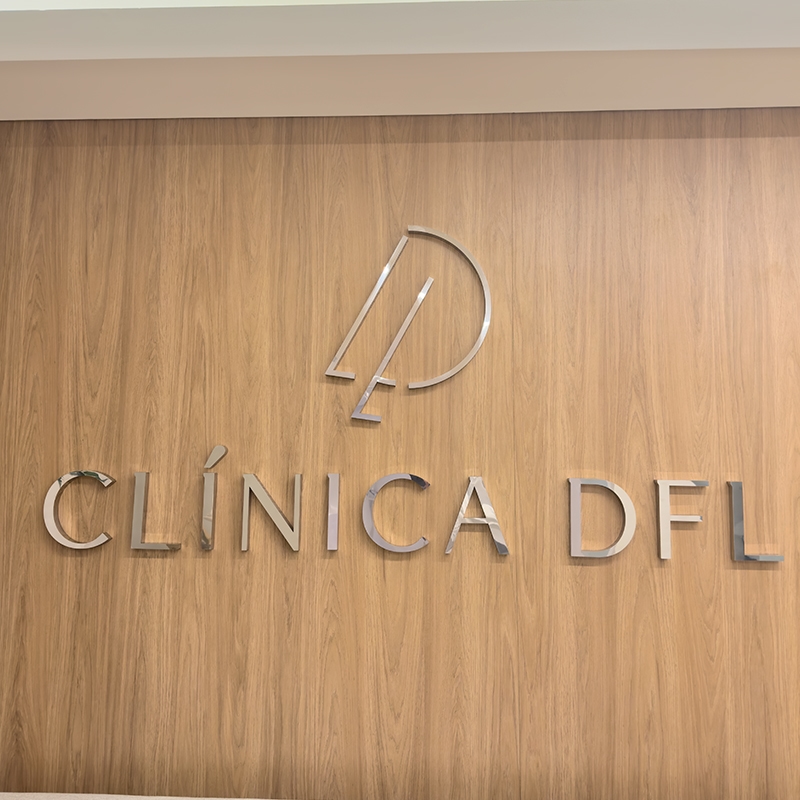 Foto da recepção da clínica com o logo da DFL metálico em um fundo amadeirado