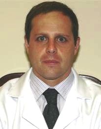Foto do Dr Alexandre Meluzzi, um homem branco de meia idade com cabelos pretos e curtos, usando um jaleco branco