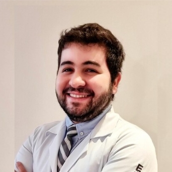 Foto do Dr Gabriel de Almeida Arruda Felix, um homem branco com cabelos pretos e curtos, usando um jaleco branco